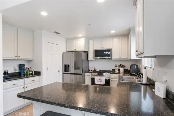 a kitchen with stainless steel appliances granite countertop a refrigerator a stove a sink a microwave and cabinets