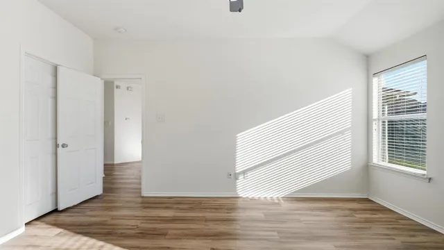 a view of empty room with wooden floor and fan