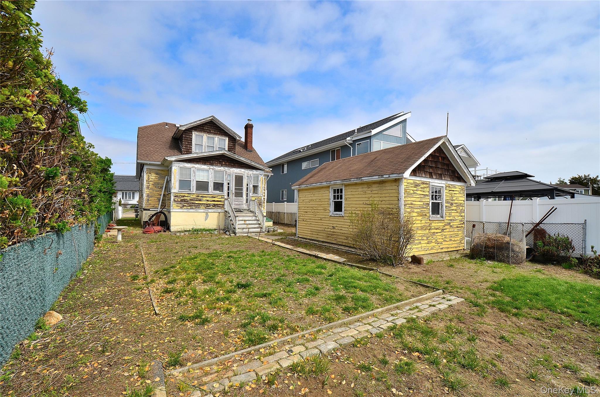 2586 Riverside Drive Wantagh, NY 11793 - Photo 8 of 9 The property features a spacious yard with a mix of lawn and natural ground, a detached garage, and a privacy hedge