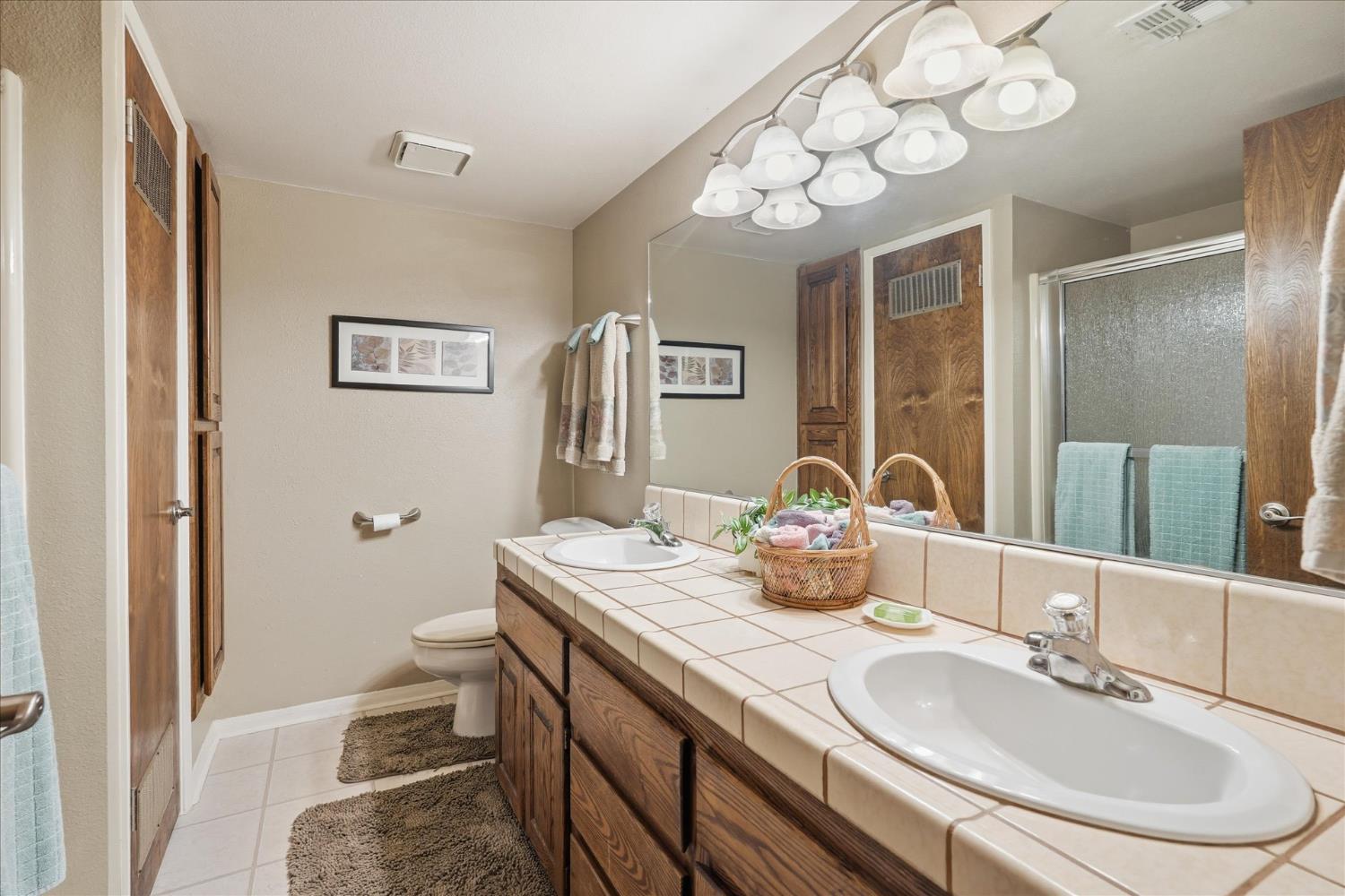 40182 Alerna Way Oakhurst, CA 93644 - Photo 22 of 49 a bathroom with a granite countertop sink a toilet and a mirror