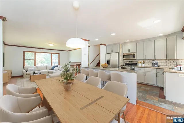 a large kitchen with kitchen island granite countertop a living room white cabinets and stainless steel appliances