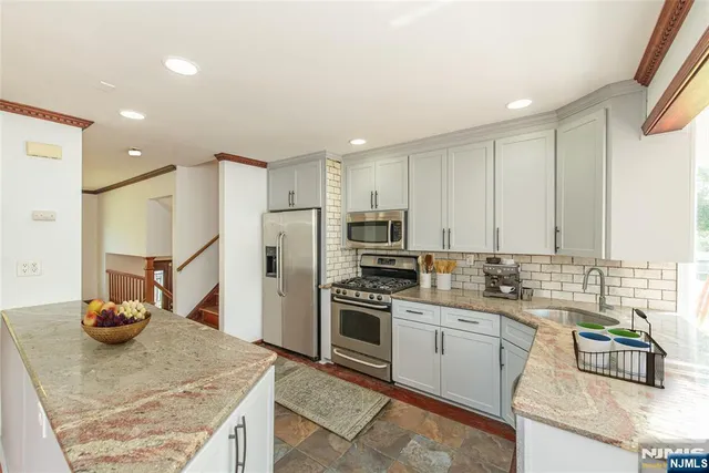 a kitchen with stainless steel appliances granite countertop a sink refrigerator and cabinets