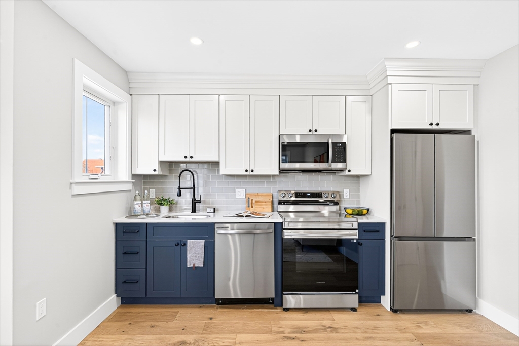 584 Cambridge Street, Unit 1 Boston, MA 02134 - Photo 1 of 17 a kitchen with stainless steel appliances granite countertop a stove a refrigerator and a sink with wooden cabinets