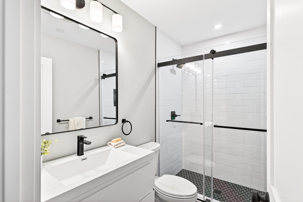 584 Cambridge Street, Unit 1 Boston, MA 02134 - Photo 11 of 17 a bathroom with a sink toilet a mirror and shower
