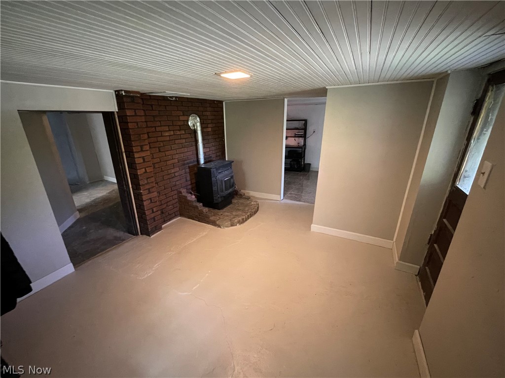 54544 Mt Victory Road Powhatan Point, OH 43942 - Photo 26 of 43 Unfurnished bedroom with concrete flooring, a wood stove, and brick wall
