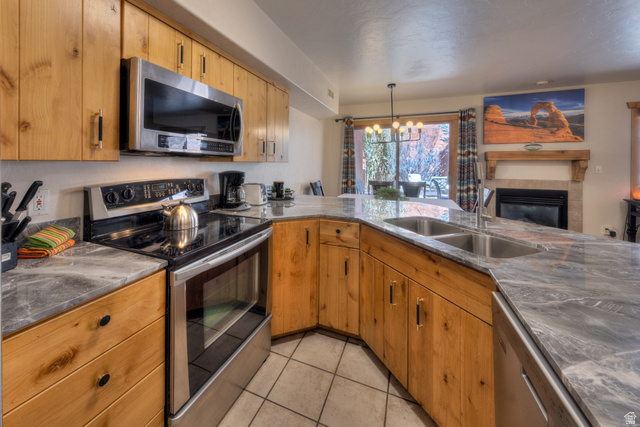 3461 Westwater Road, Unit 6 Moab, UT 84532 - Photo 32 of 33 Kitchen with stainless steel appliances, hanging lights, a tiled fireplace, wood finish cabinetry, and open floor plan