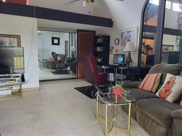 a living room with furniture a flat screen tv and floor to ceiling window