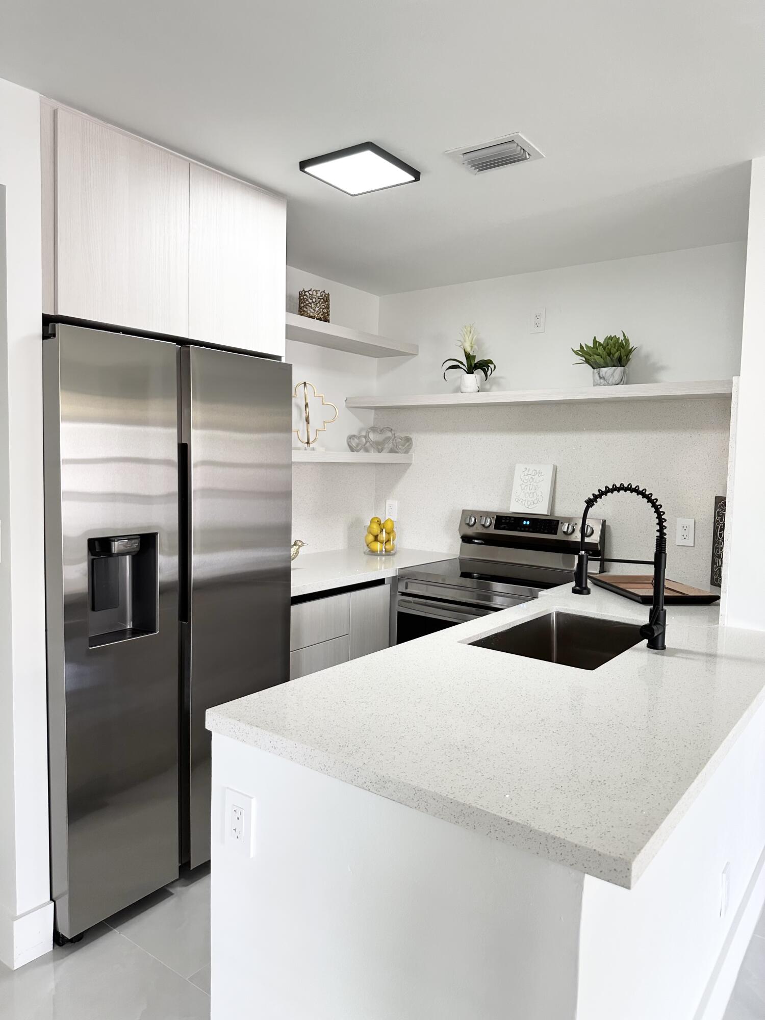 10033 Winding Lake Road, Unit 204 Sunrise, FL 33351 - Photo 10 of 37 a kitchen with stainless steel appliances a sink a stove and a refrigerator with wooden floor
