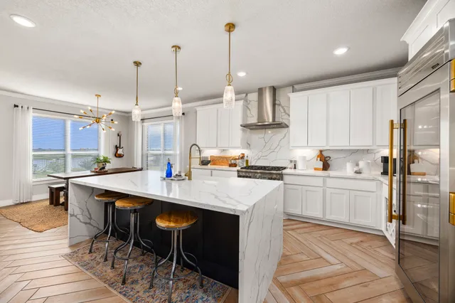a kitchen with stainless steel appliances kitchen island granite countertop a table chairs sink and cabinets