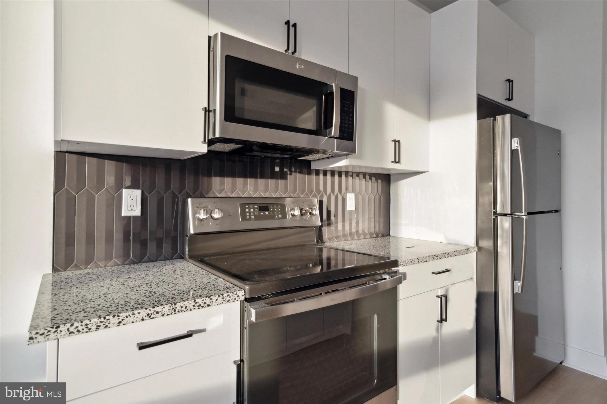 1643 North 2nd Street, Unit 302 Philadelphia, PA 19122 - Photo 36 of 40 a kitchen with stainless steel appliances granite countertop a stove microwave and refrigerator