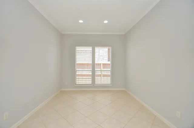 a view of an empty room with kitchen and window