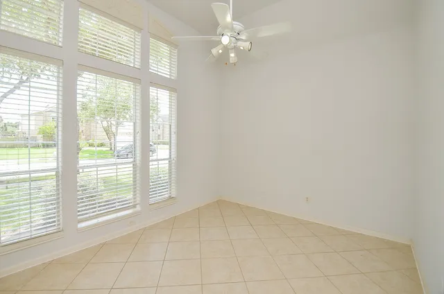 a view of an empty room with window and chandelier fan