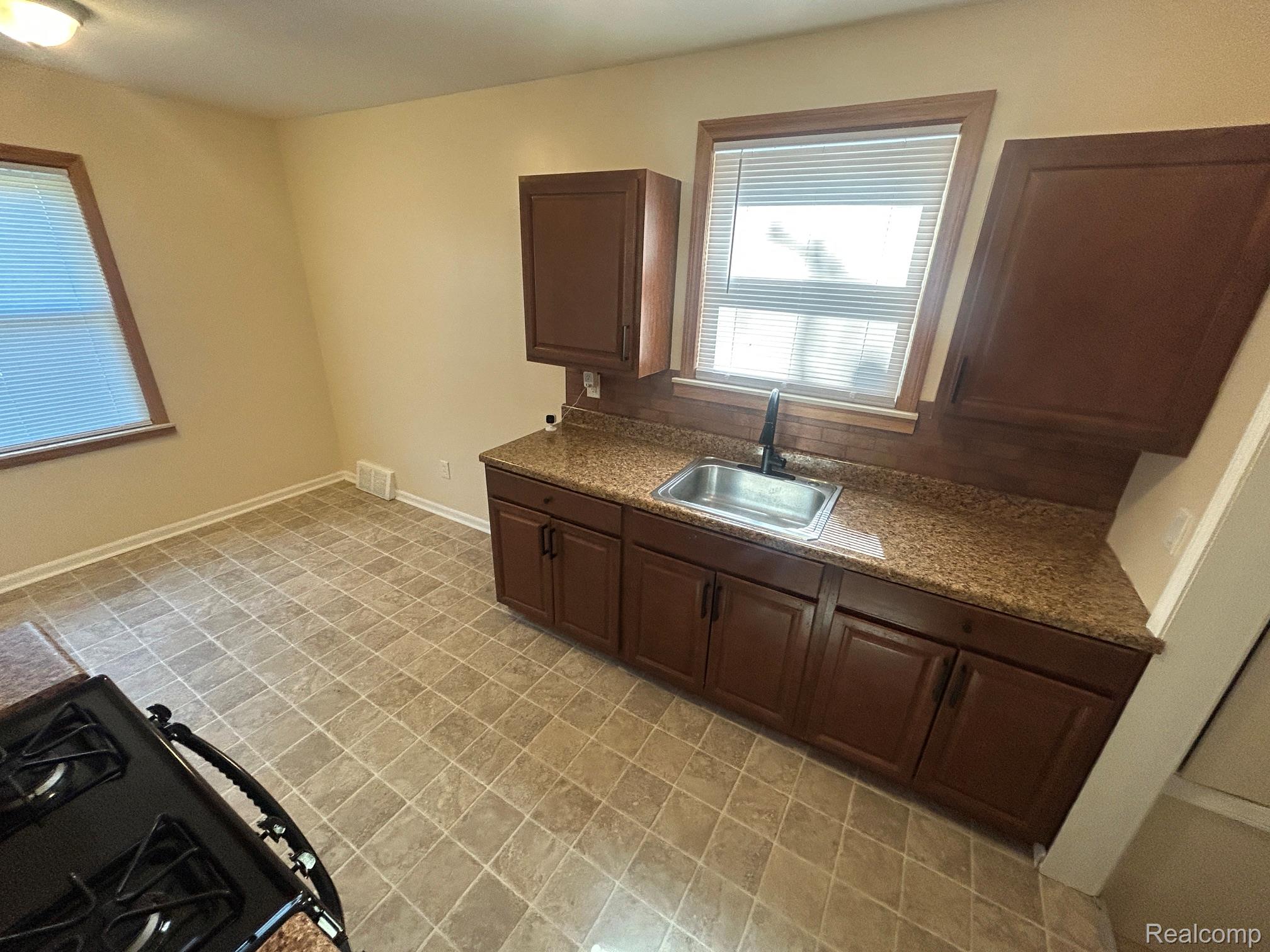 21970 Moross Road Grosse Pointe, MI 48236 - Photo 4 of 21 Kitchen featuring ample cabinetry, a stainless steel sink with a matte black faucet, granite-finish countertops, and tiled flooring