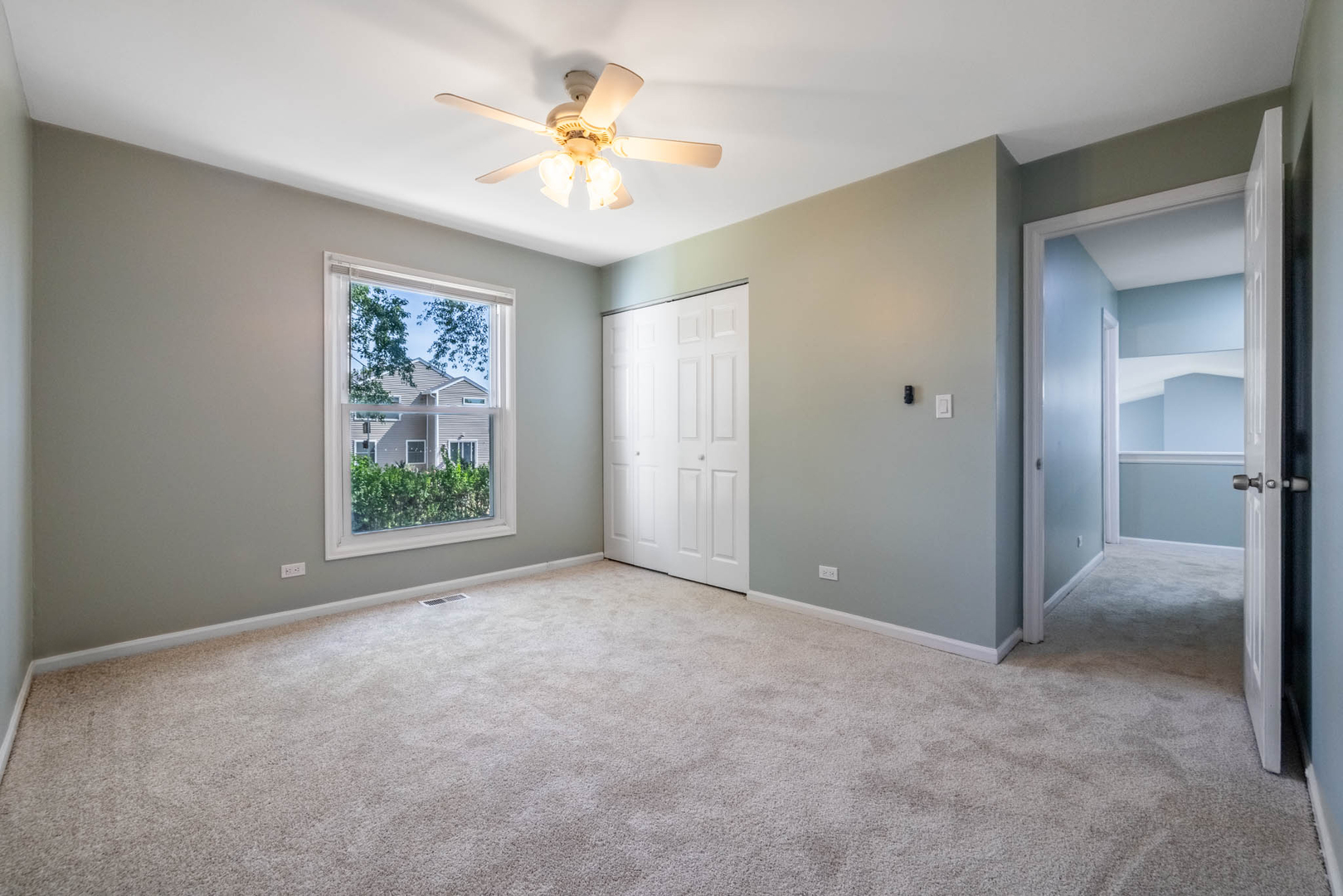 983 Stuart Drive Bartlett, IL 60103 - Photo 16 of 25 an empty room with a chandelier fan and a window