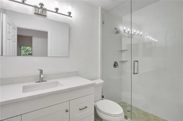 a bathroom with a sink toilet a mirror and shower