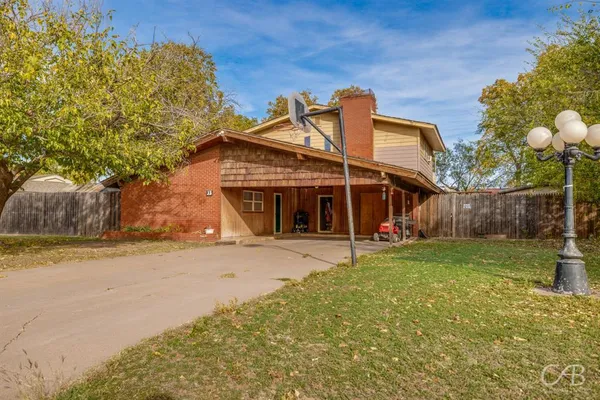 a view of a house with a backyard and basketball court