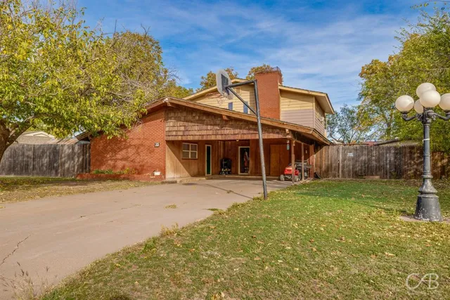a view of a house with a backyard and basketball court