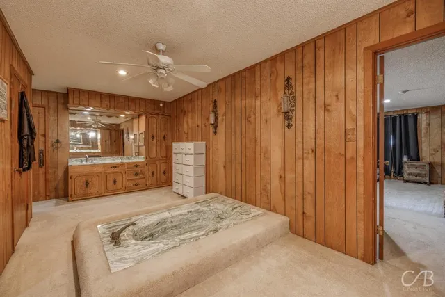 a spacious bedroom with a large bed a chandelier and closet