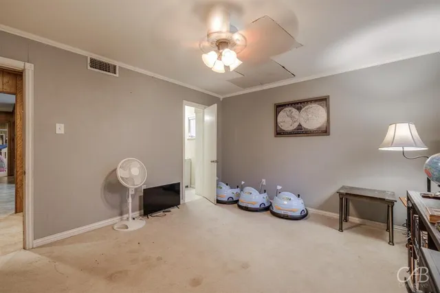 a view of an empty room with wooden floor and fan