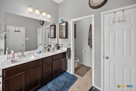 a spacious bathroom with a double vanity sink a mirror and a shower