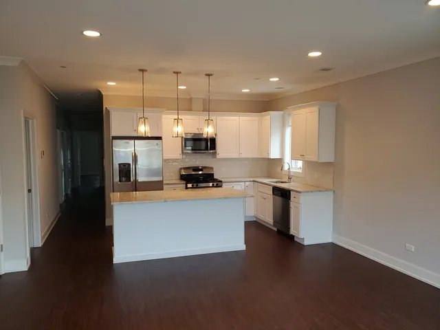 a large kitchen with kitchen island a sink wooden floor and stainless steel appliances