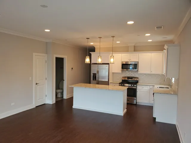 a kitchen with stainless steel appliances a stove a sink a refrigerator and a microwave