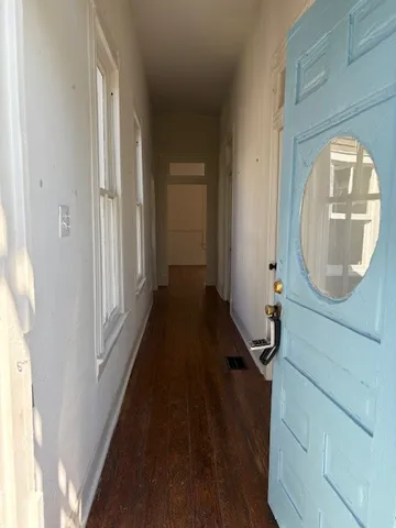 a view of a hallway with wooden floor and a mirror
