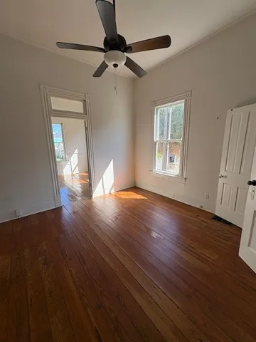 a view of an empty room with wooden floor and a window