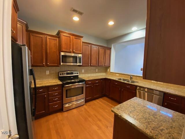 10103 Falls Meadow Court Raleigh, NC 27617 - Photo 28 of 54 a kitchen with stainless steel appliances granite countertop wooden cabinets a stove a sink and a refrigerator