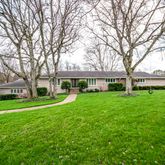 a view of a house with a big yard and large trees
