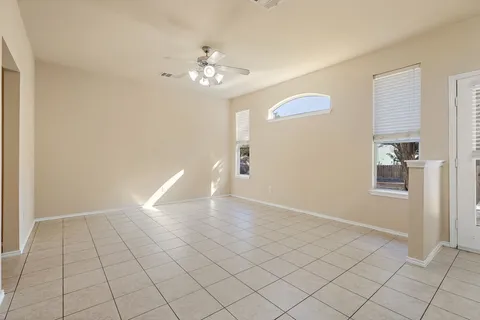 a view of an empty room with window and chandelier fan