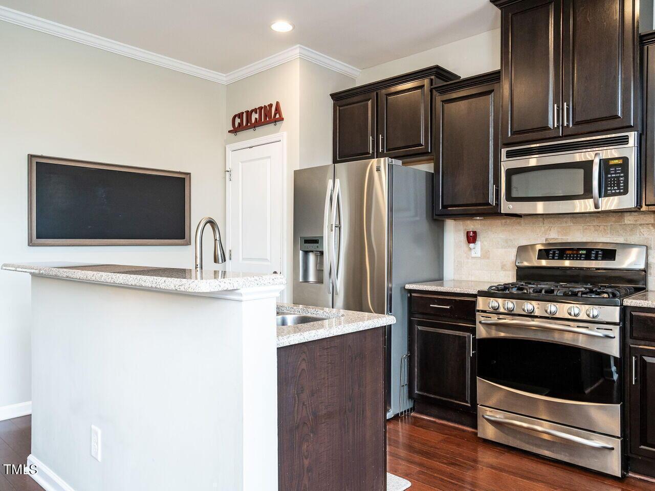 1316 Cornell Place Raleigh, NC 27607 - Photo 5 of 31 a kitchen with stainless steel appliances and wooden cabinets