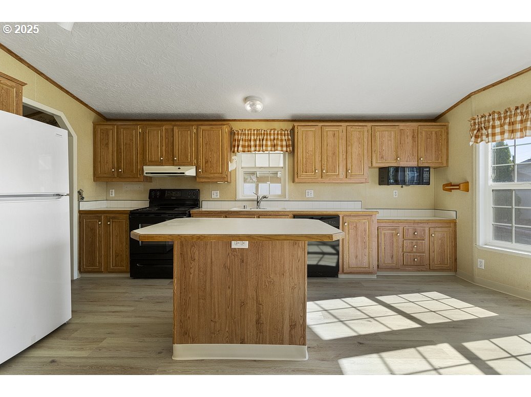1949 Southeast Palmquist Road, Unit 100 Gresham, OR 97080 - Photo 13 of 28 a kitchen with a refrigerator a sink and wooden cabinets