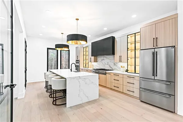 a kitchen with stainless steel appliances kitchen island granite countertop a refrigerator a stove and a sink with wooden floor