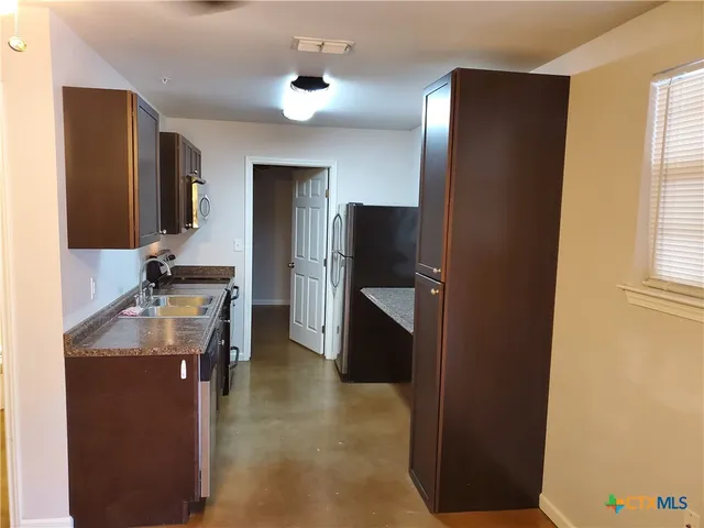 a kitchen with granite countertop a refrigerator and a stove top oven