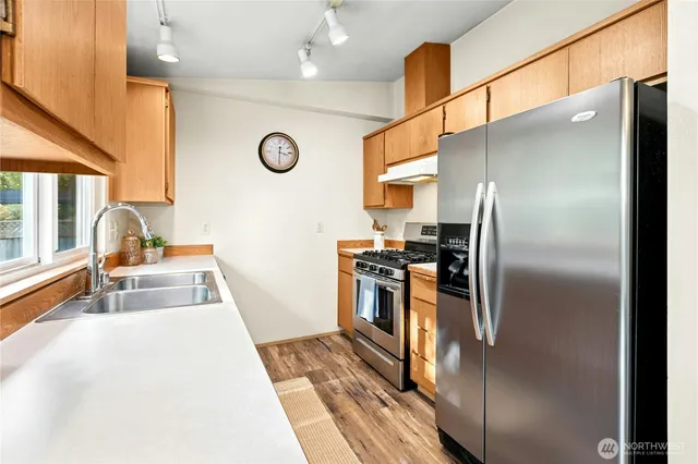 a kitchen with stainless steel appliances granite countertop a refrigerator a stove and a sink