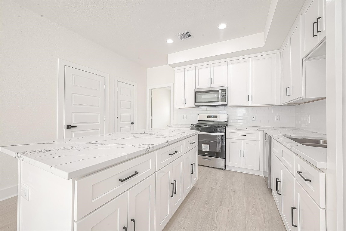 4135 Mallow Street, Unit B Houston, TX 77051 - Photo 8 of 11 a kitchen with granite countertop white cabinets and white appliances