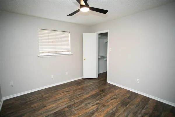 an empty room with wooden floor chandelier fan and windows