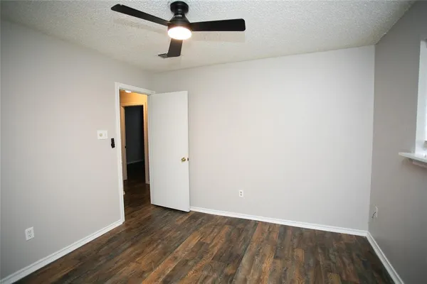 an empty room with wooden floor cabinet and a ceiling fan