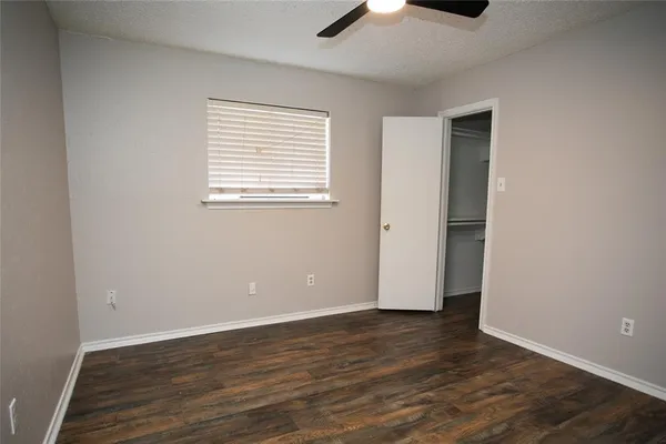 an empty room with wooden floor cabinet and windows