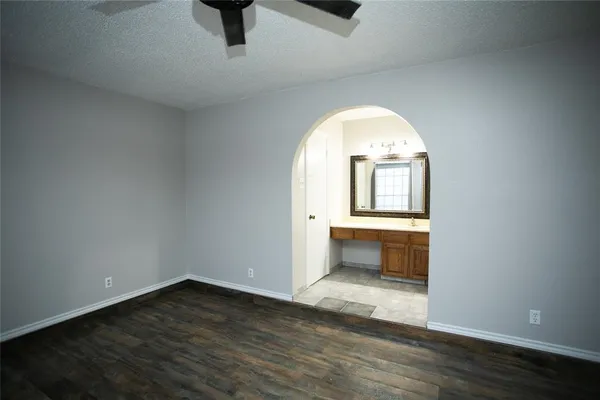 an empty room with wooden floor cabinet and windows