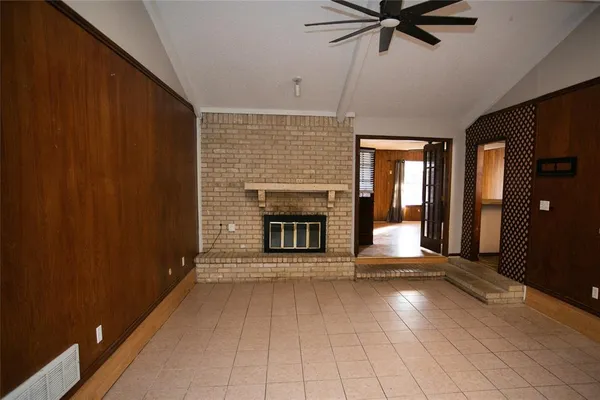 a view of a livingroom with a fireplace a ceiling fan and window