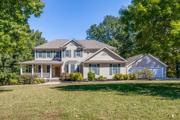 a front view of a house with a yard and large trees