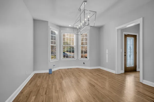 a view of an empty room with wooden floor and windows