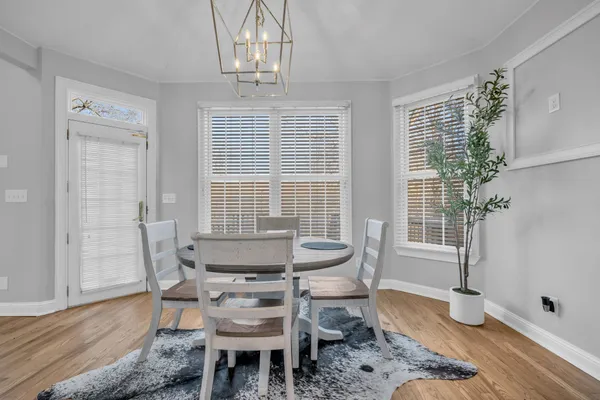 a dining room with wooden floor a chandelier a glass table and chairs