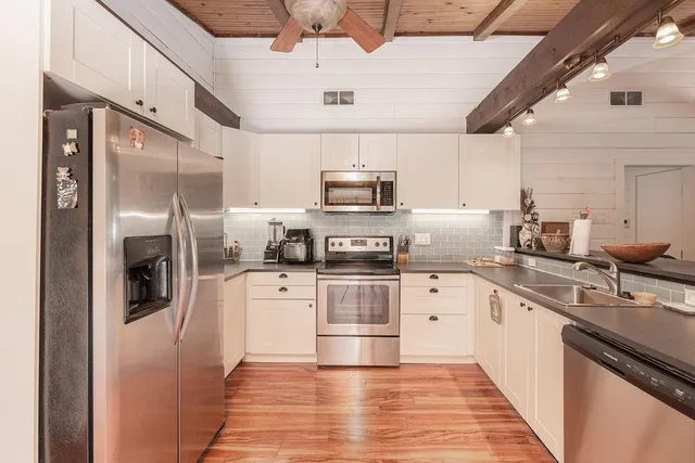 a kitchen with stainless steel appliances granite countertop a refrigerator a stove and a sink