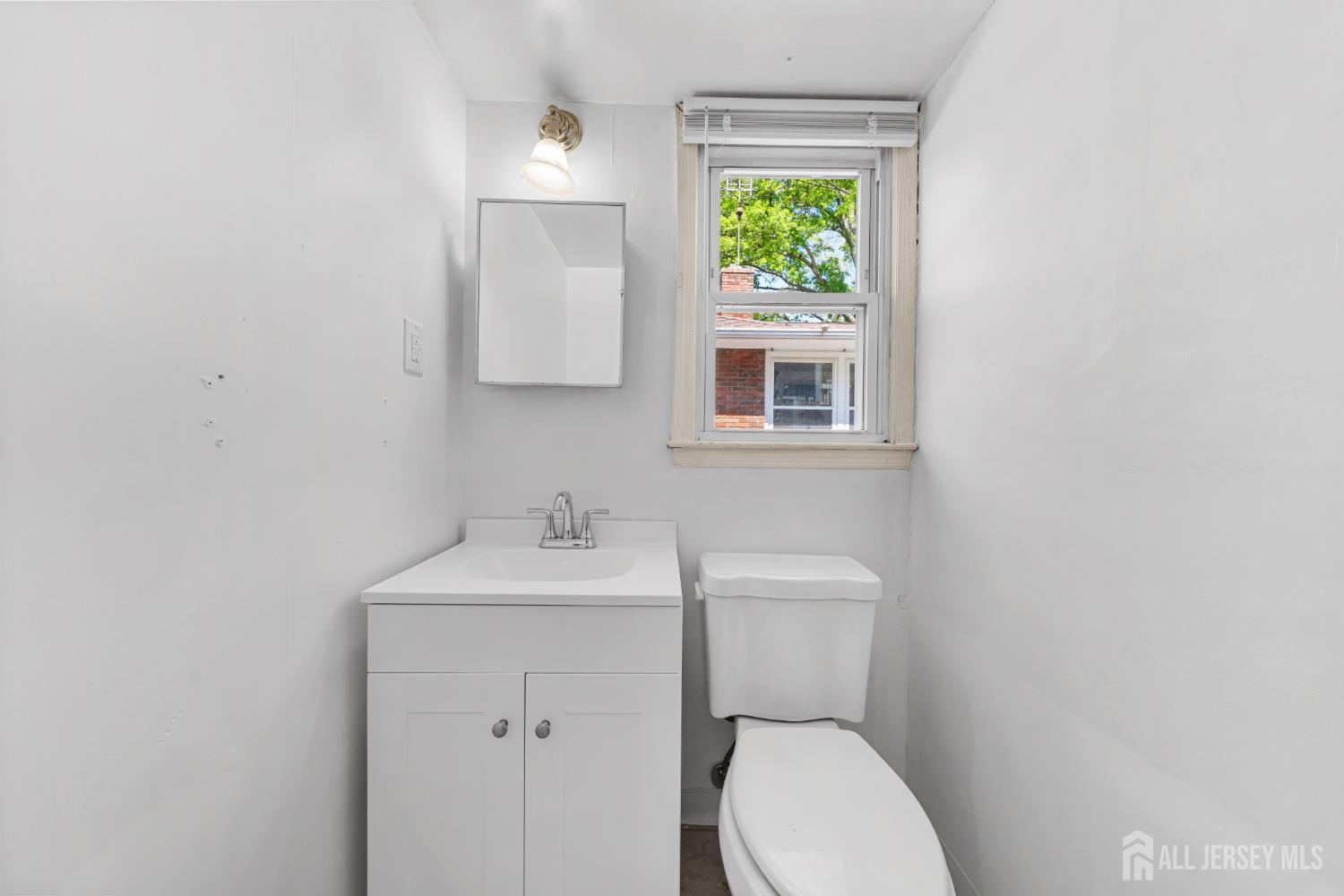 245 4th Street Dunellen, NJ 08812 - Photo 21 of 27 a bathroom with a toilet a sink and mirror