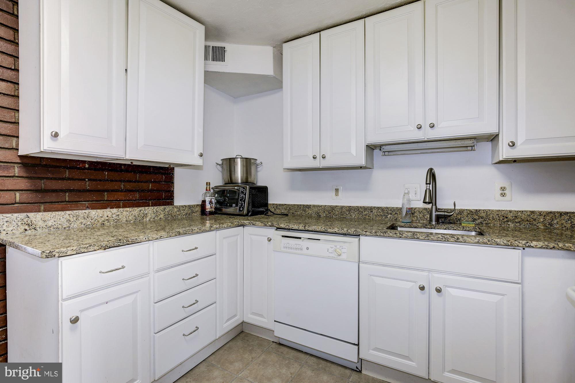 5705 Denfield Road Rockville, MD 20851 - Photo 9 of 20 a kitchen with granite countertop white cabinets and white appliances