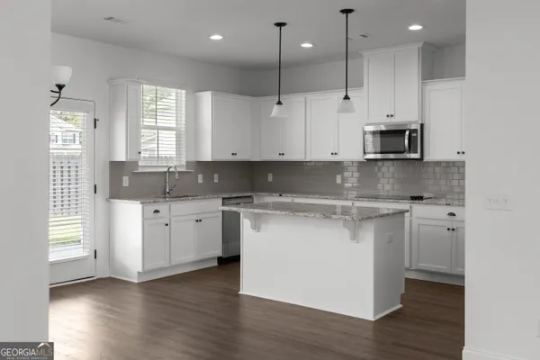 a kitchen with stainless steel appliances granite countertop a sink a stove and a wooden floors
