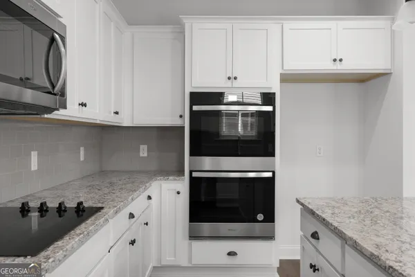 a kitchen with granite countertop white cabinets and black appliances